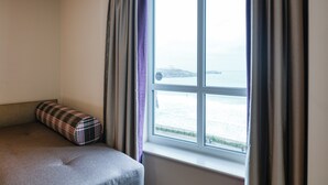 A room with a bed, a window with curtains, and a view of the sea. - Premier Inn Newquay (Newquay)