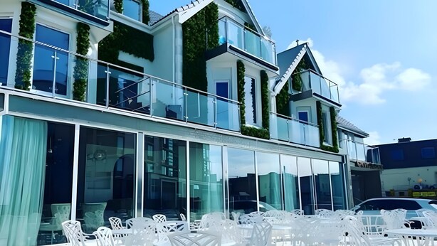 A modern building with large windows and a balcony with white chairs. - Premier Inn Newquay (Newquay)