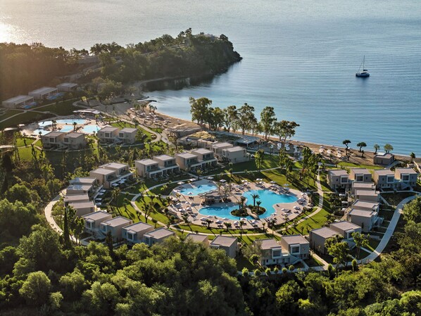 A resort with multiple buildings, a central pool, and a beach area. - Ikos Odisia (Corfu)