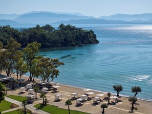 Un complexe hôtelier de bord de mer doté de chaises longues, de parasols et offrant une vue sur la mer et les montagnes.