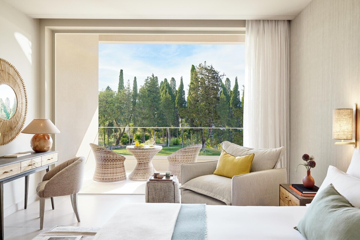 Une chambre d’hôtel moderne dotée d’un balcon, d’un lit, d’un canapé et d’un bureau avec une lampe.