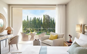 A modern hotel room with a balcony, a bed, a sofa, and a desk with a lamp. - Ikos Odisia (Corfu)