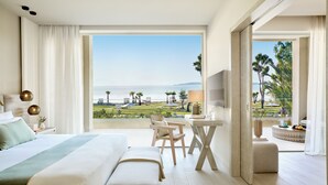 Une chambre d’hôtel avec un grand lit, un bureau, une télévision et un balcon donnant sur la mer.