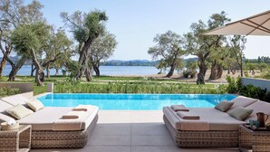 Un espace aménagé au bord de la piscine, avec deux canapés en osier, une petite table et une vue sur la mer.