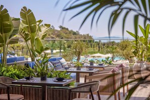 Un espacio de comedor al aire libre con mesas, sillas y plantas en macetas.