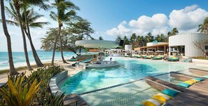 Área de piscina do resort com espreguiçadeiras, uma banheira de hidromassagem e vista para o oceano.