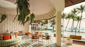A poolside area with a circular seating arrangement, a pool, and palm trees in the background. - Avani Chaweng Samui Hotel and Beach Club (Koh Samui)