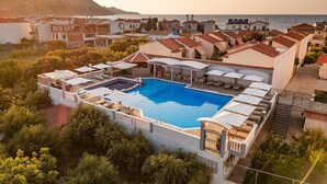 A resort with a swimming pool, outdoor seating, and a view of the sea. - Athena Beach (Samos)