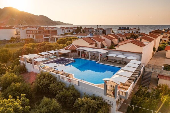 A resort with a swimming pool, outdoor seating, and a view of the sea. - Athena Beach (Samos)