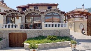 A hotel with a stone facade, large arched windows, and a sign reading "Athena Hotel." - Athena Beach (Samos)