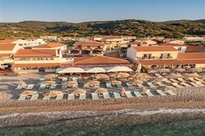 A coastal town with beachside buildings, rows of beach umbrellas, and a clear view of the sea. - Athena Beach (Samos)