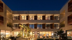 Ein mehrstöckiges Hotel mit Balkonen, großen Fenstern und Außenbereichen zum Sitzen.