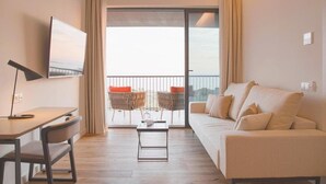 Ein modernes Wohnzimmer mit einer Couch, einem Couchtisch, einem Fernseher und einem Balkon mit Blick.
