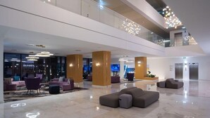 Eine geräumige Lobby mit modernen Sitzgelegenheiten, einer Glastrennwand und einer zentralen Säule.