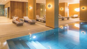 Ein moderner Poolbereich im Innenbereich mit Liegestühlen und klarem Wasser.