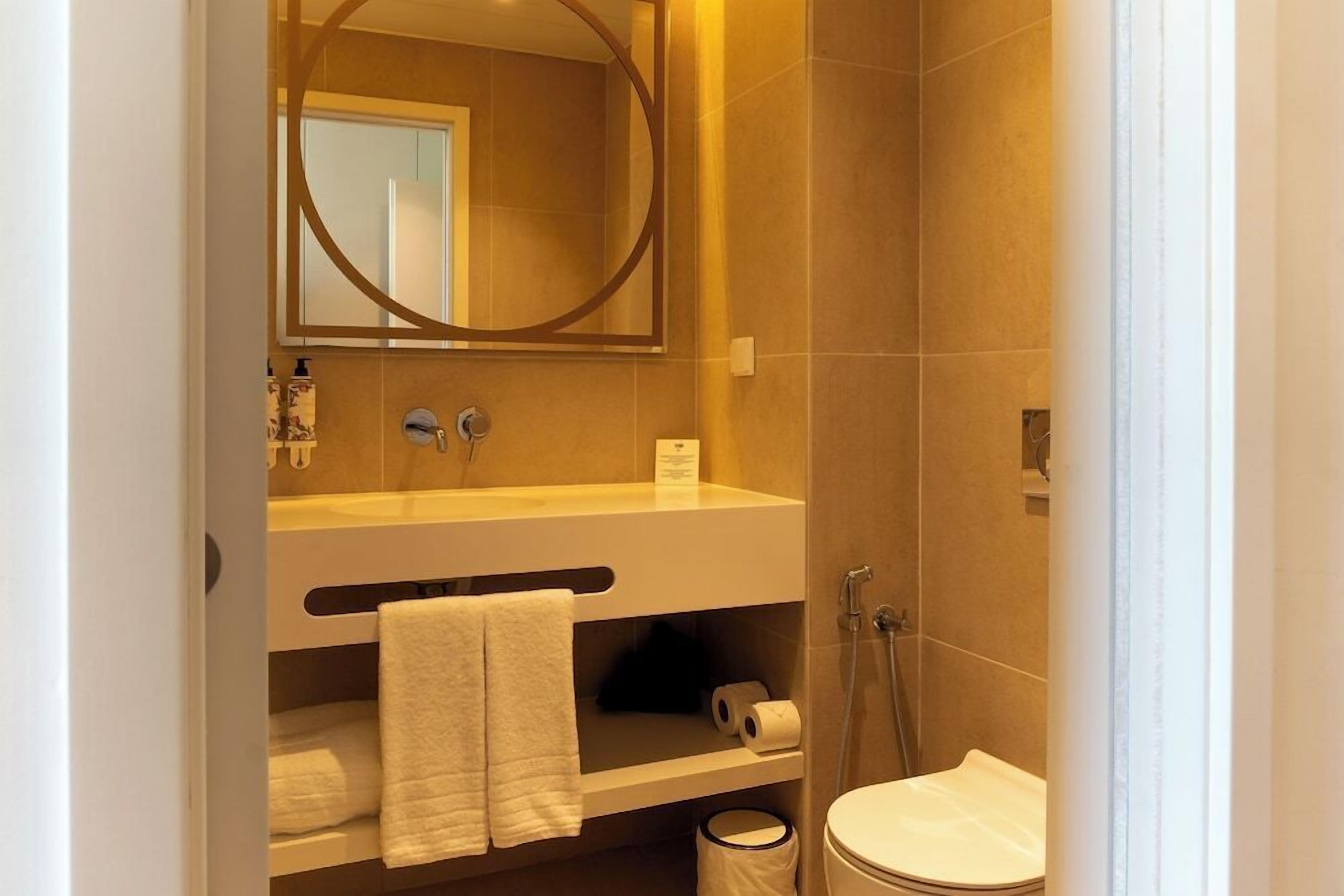 Un baño moderno con inodoro, lavamanos y espejo.