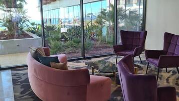 Un interior moderno con un sofá rosa, sillones morados y una mesa de centro de vidrio.
