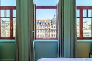 Et hotelværelse med et stort vindue, gardiner og en seng.