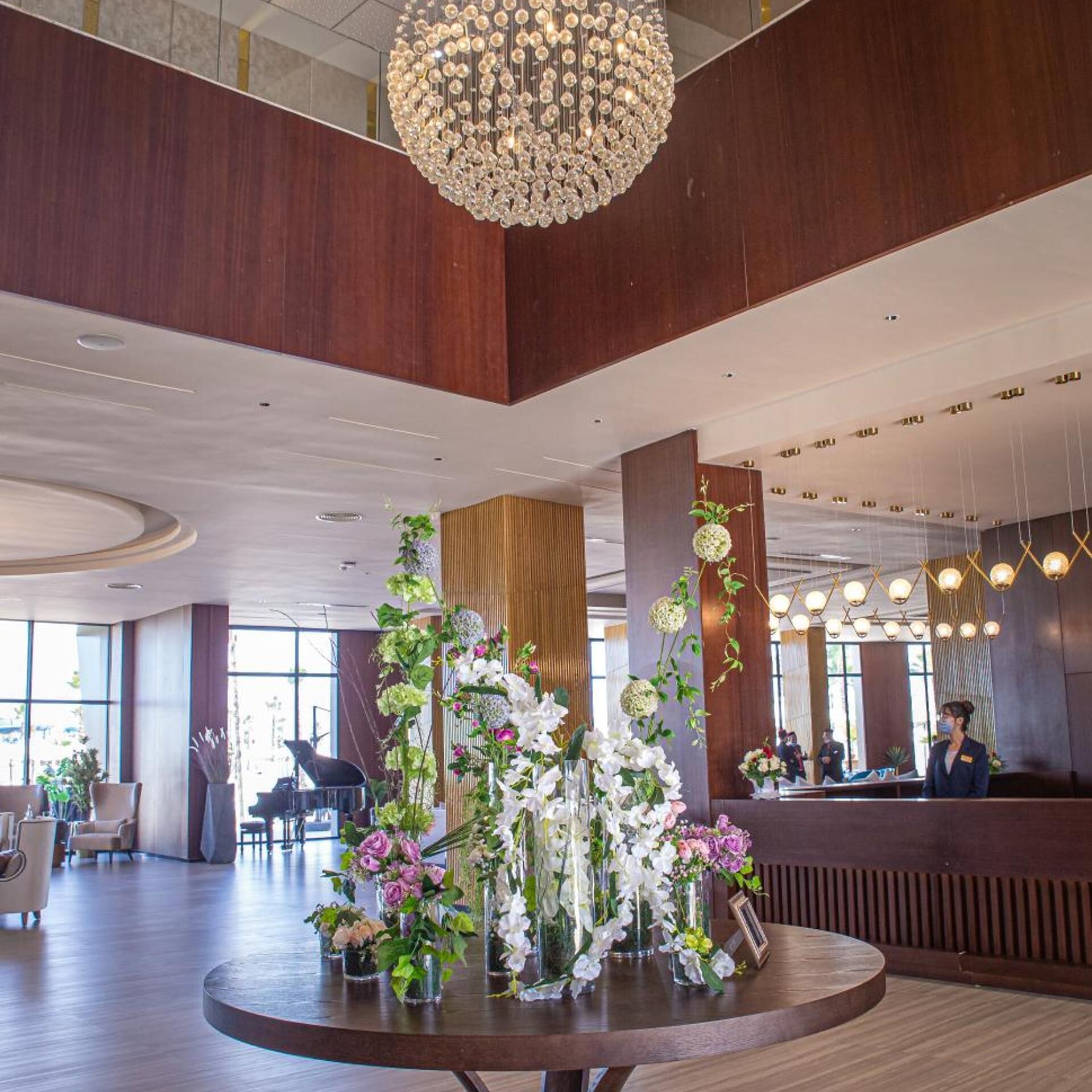 A spacious lobby with a grand chandelier, a reception desk, and a piano.