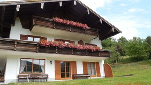 A two-story building with wooden balconies and flower boxes. - Vacation apartment 60 sqm, 2-4 persons, 2 bedrooms, eat-in kitchen, 2 bathrooms (Unterwössen)