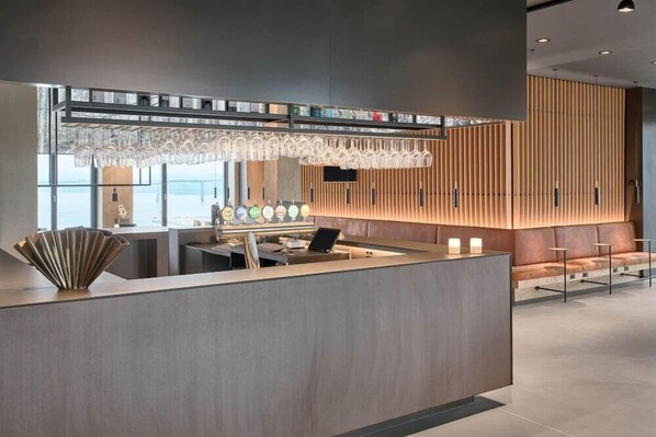 A modern reception area with a wooden panel wall, a glass display case, and a seating area with a sofa and chairs. - Zleep Hotel Vejle (Vejle)