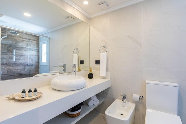 Un bagno moderno con uno specchio grande, un lavandino rotondo, un bidet e un water.