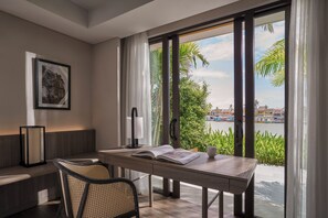 A modern room with a large window, a desk, a chair, a lamp, and a framed picture on the wall. - Moire Hoi An, Vignette Collection (Hoi An)