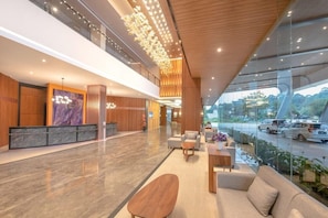 A spacious lobby with a reception desk, seating area, and large windows offering a view of the outside. - FOX Harris Hotel and Convention Banjarnegara (Banjarnegara)