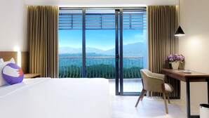 A hotel room with a bed, a desk, a chair, and a view of mountains through a sliding door. - FOX Harris Hotel and Convention Banjarnegara (Banjarnegara)