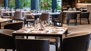 A restaurant with tables set for dining, large windows, and indoor plants. - Crowne Plaza Danang City Centre by IHG (Da Nang)