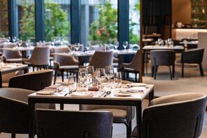 A restaurant with tables set for dining, large windows, and indoor plants. - Crowne Plaza Danang City Centre by IHG (Da Nang)