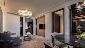 A modern living room with a marble table, two sofas, a chandelier, and a TV. - Crowne Plaza Danang City Centre by IHG (Da Nang)