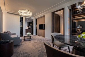 A modern living room with a marble table, two sofas, a chandelier, and a TV. - Crowne Plaza Danang City Centre by IHG (Da Nang)