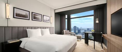 Habitación de hotel moderna con una cama grande, un escritorio y vistas a la ciudad.