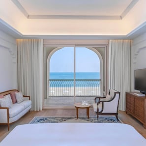 A hotel room with a large arched window, a sofa, a chair, a small table, and a TV. - The Chedi Katara Hotel and Resort - a GHM Hotel (Doha)