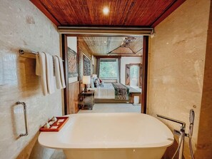 A modern bathroom with a freestanding bathtub, a towel rack, and a shower area. - Sakti Garden Resort and Spa (Ubud)