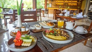 A breakfast buffet with various dishes, including fruits, vegetables, and eggs, set on a wooden table in a restaurant. - Sakti Garden Resort and Spa (Ubud)