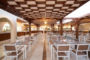 A spacious dining area with multiple tables and chairs, a central bar, and a pool area. - Xanadu Makadi Bay (Makadi Bay)