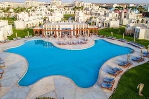 A large, curved swimming pool with lounge chairs and umbrellas around its perimeter. - Xanadu Makadi Bay (Makadi Bay)