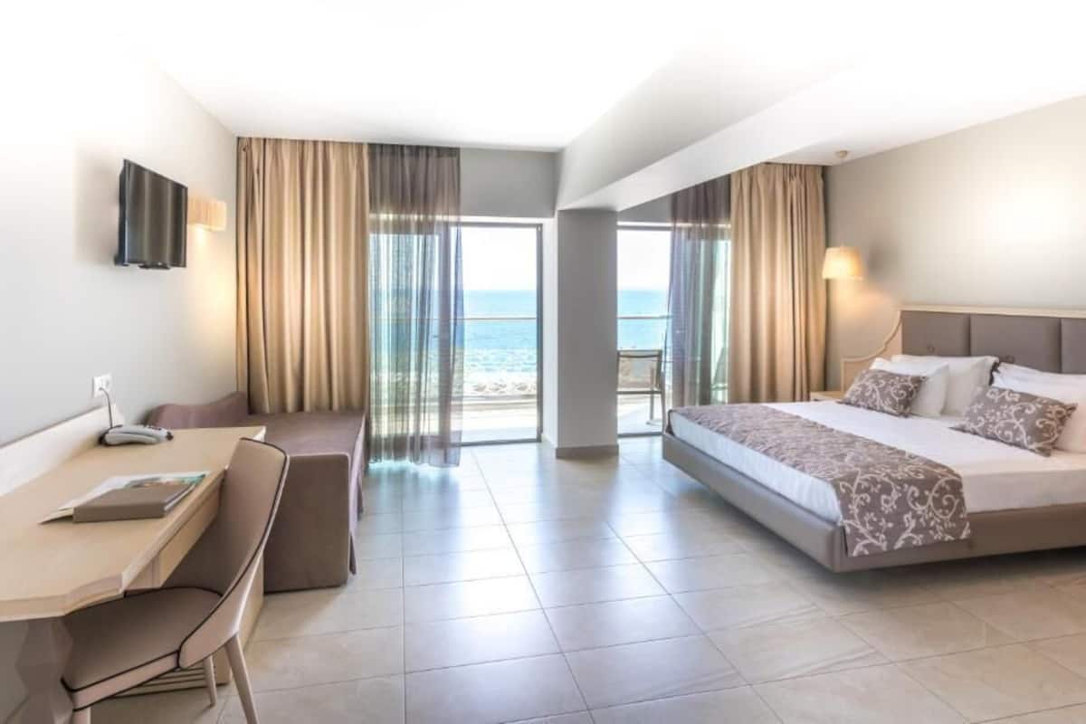 A hotel room with a bed, a desk, a chair, and a TV.
