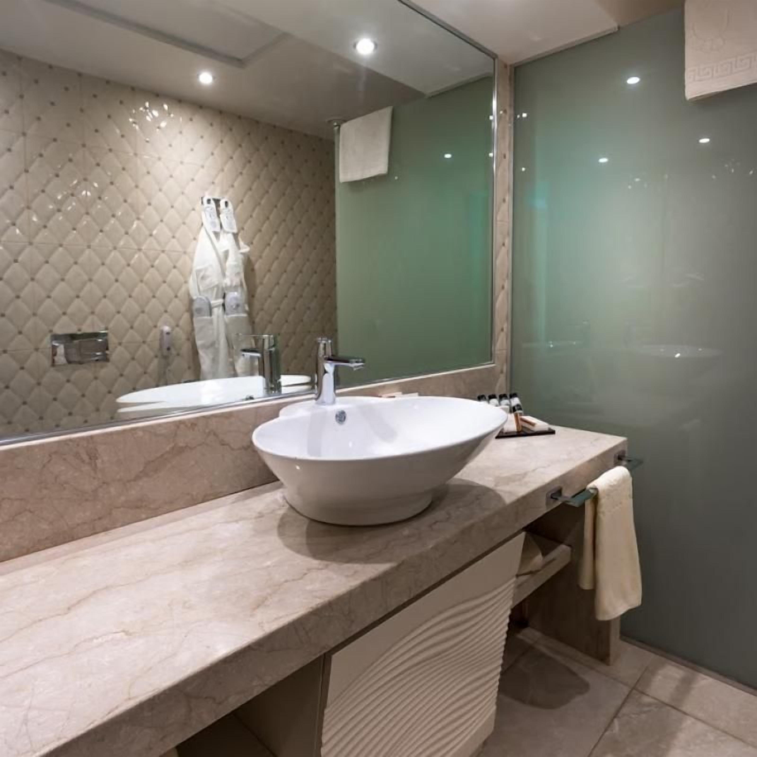 A modern bathroom with a large mirror, a vessel sink, and a glass shower enclosure.