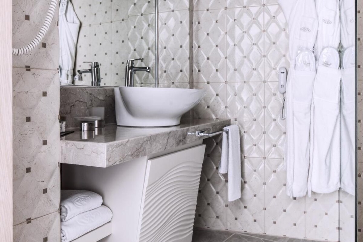 Un baño moderno con lavamanos de mármol, un perchero y una cortina de ducha.