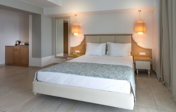 A hotel room with a large bed, bedside tables, a wooden cabinet, and a mirror.