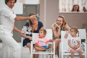 A family seated at an outdoor table with white chairs, a waiter serving drinks, and a casual dining atmosphere. - Elinotel Sermilia (Polygyros)
