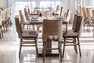 A dining area with long tables, chairs, and wine glasses.