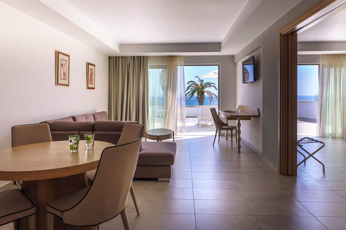 Een moderne hotelkamer met een zithoek, een bank, een kleine tafel en een aan de muur bevestigde televisie.