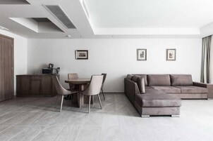 Una sala de estar moderna con comedor, un sofá y una zona de cocina con microondas.