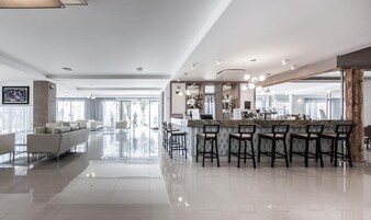 Un moderno vestíbulo de hotel con zona de bar, asientos y vistas al exterior.