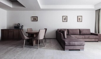 Una sala moderna con sofá, mesa de comedor, sillas y una zona de cocina con microondas.