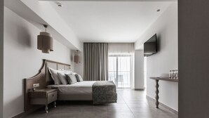 Een moderne hotelkamer met een bed, nachtkastje, lamp, televisie en uitzicht op het omliggende landschap.